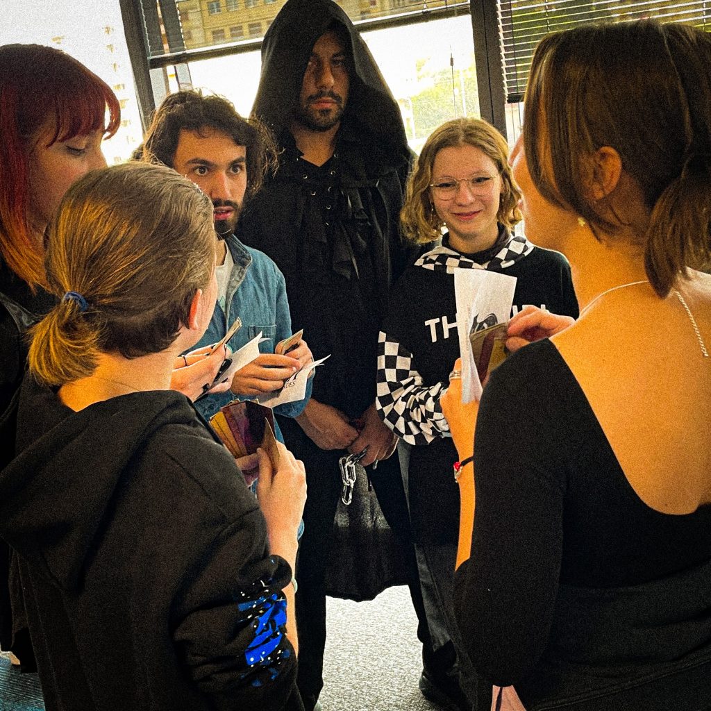 joueurs d'un jeu immersif avec des cartes à jouer en main autour de deux personnages dont un sorcier et une game master